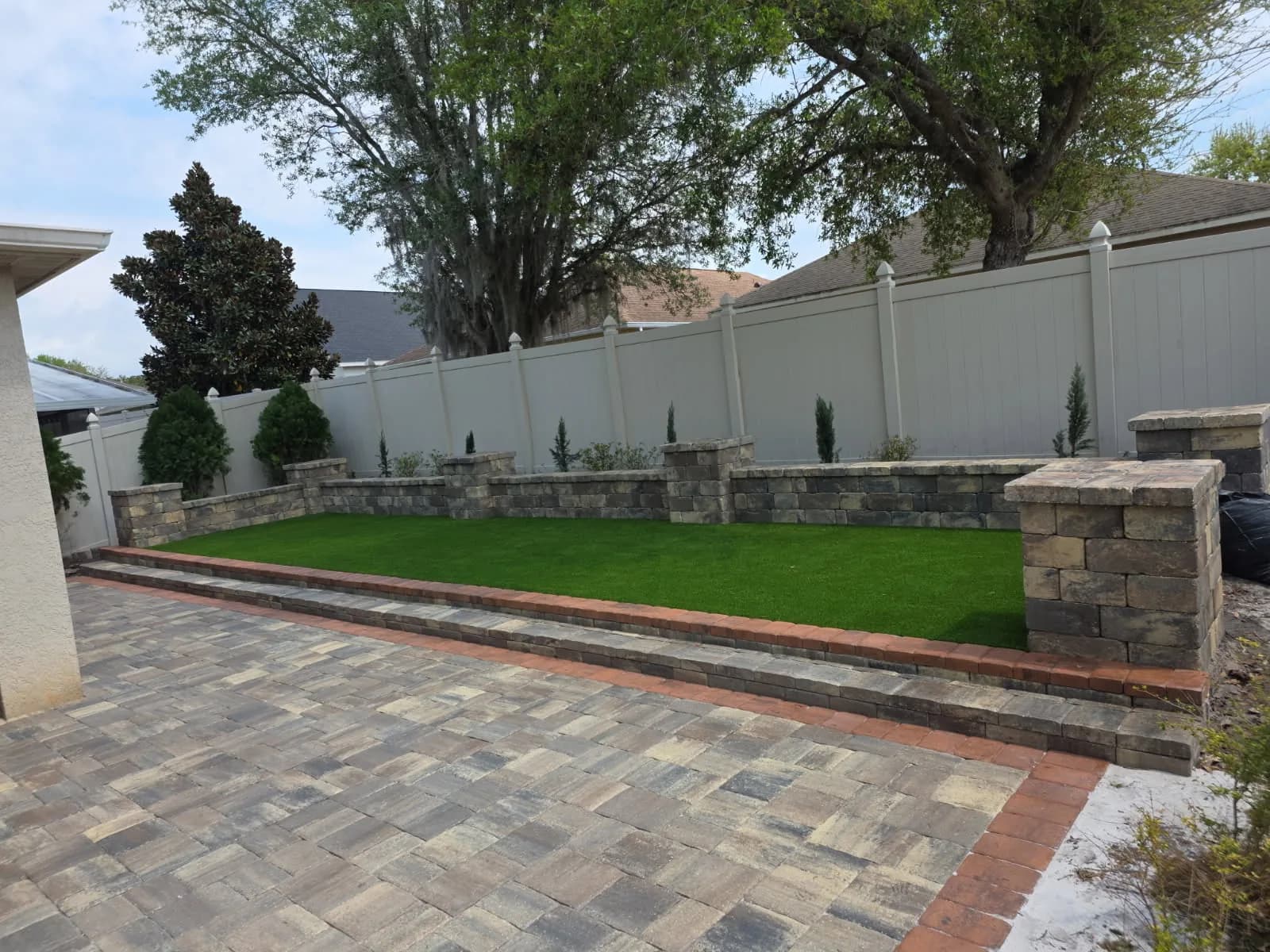 Paver patio with stacked-stone wall and turf